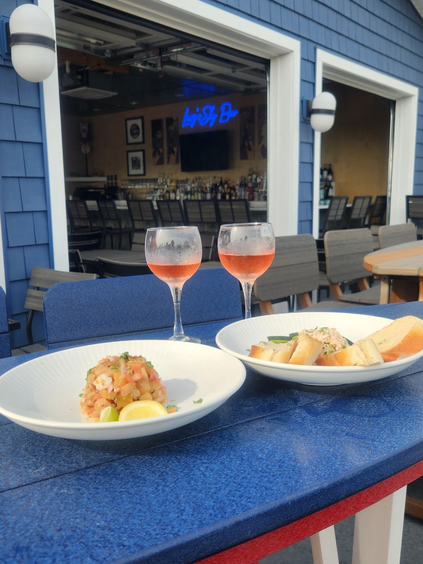 Wine, ceviche, and lobster salad on a patio table outside at Lucy's Sky Bar in Virginia Beach